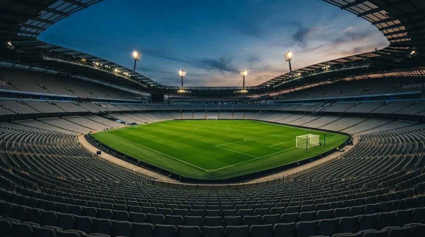 Een leeg voetbalstadion met lichtmasten bij schemering