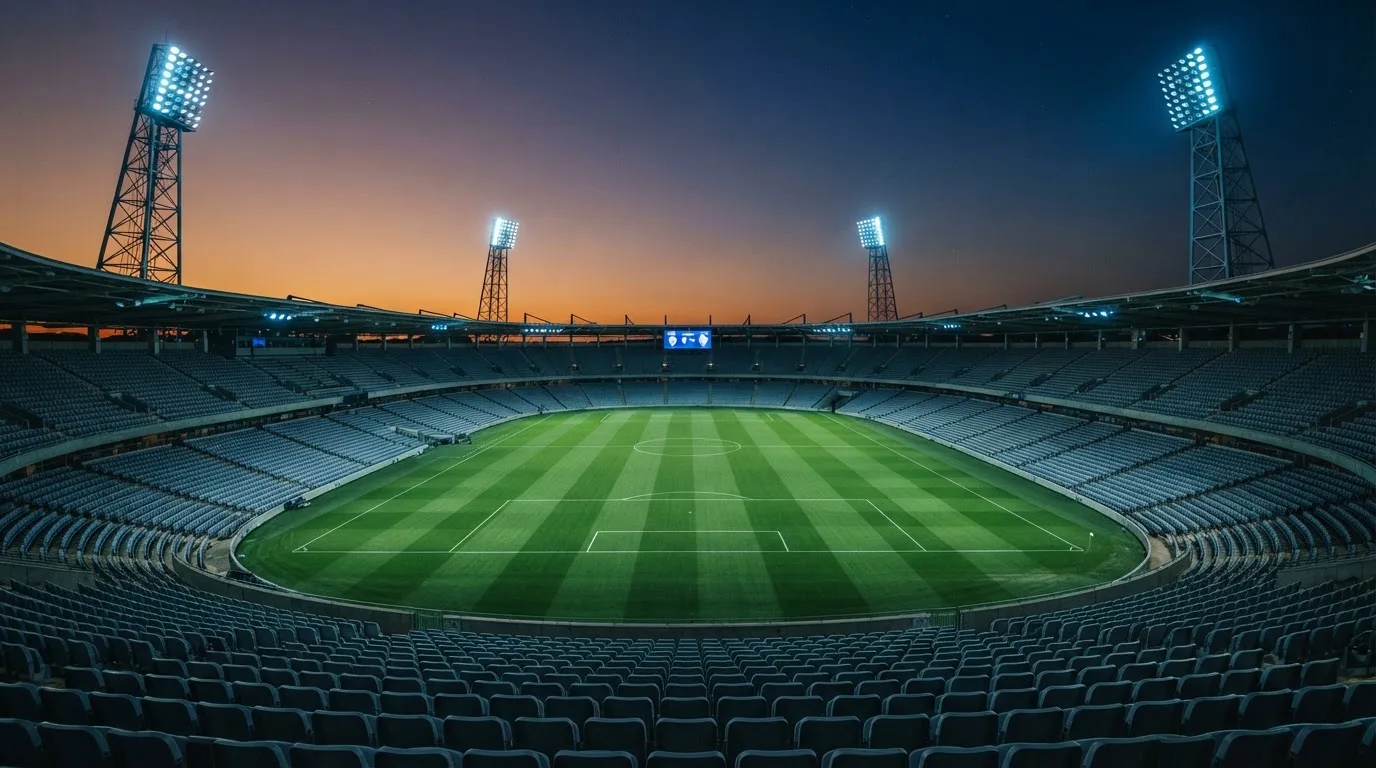Een leeg voetbalstadion met lichtmasten bij schemering