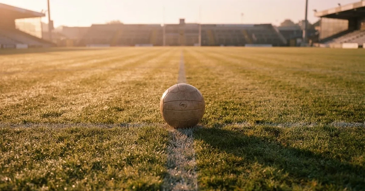 Een voetbal op de middenstip van een grasveld in het ochtendlicht