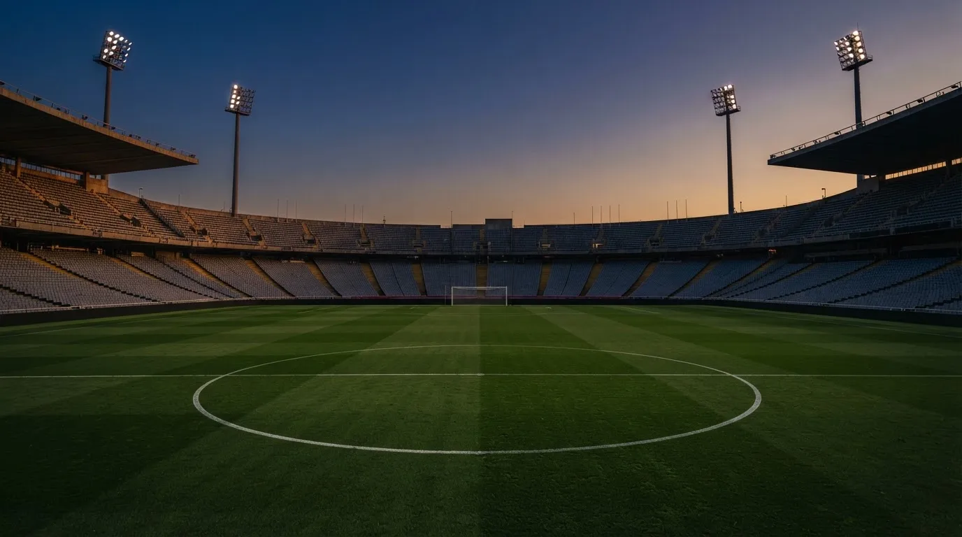 Een leeg voetbalstadion met lichtmasten bij schemering
