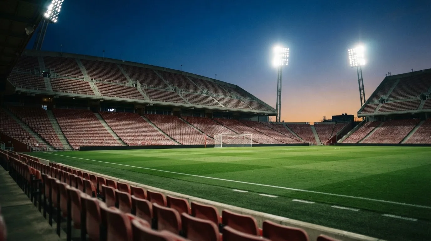 Een leeg voetbalstadion met lichtmasten bij schemering