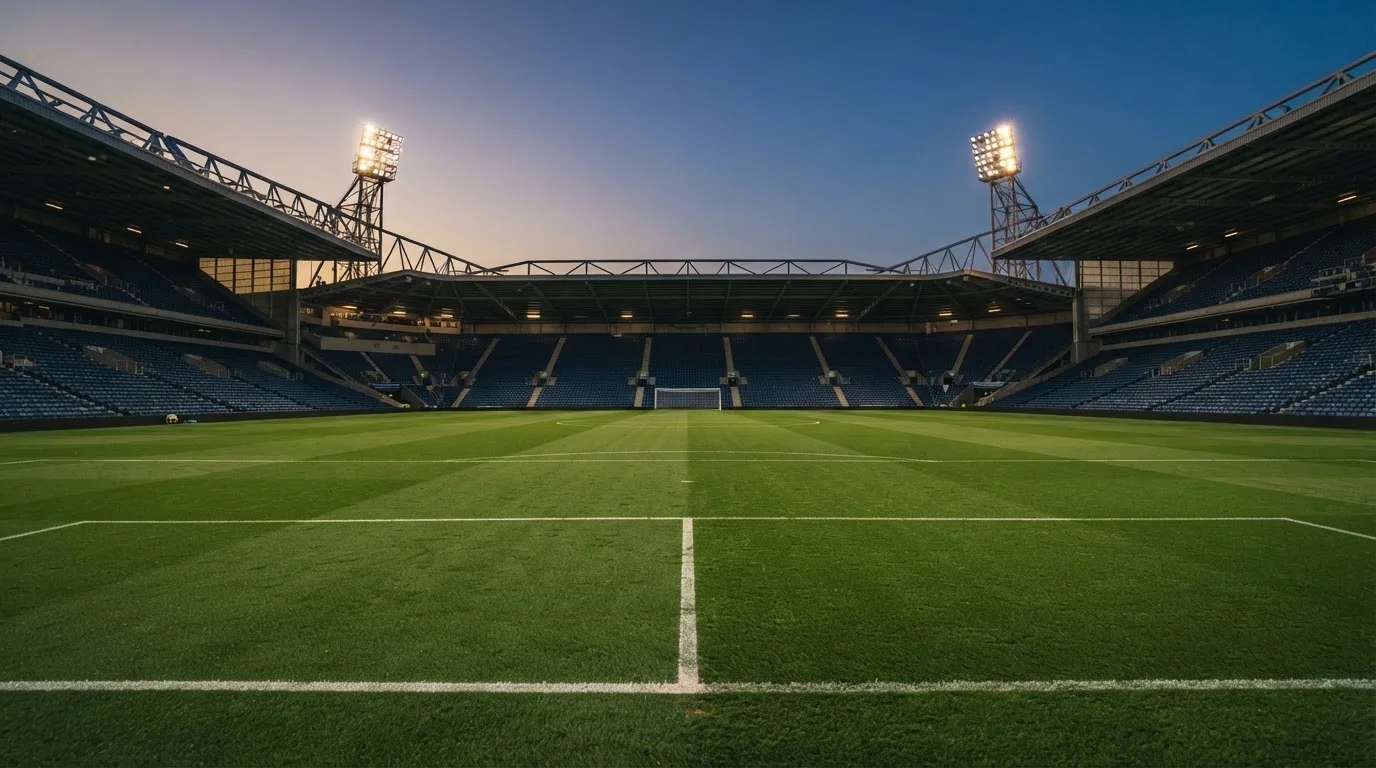 Een leeg voetbalstadion met lichtmasten bij schemering