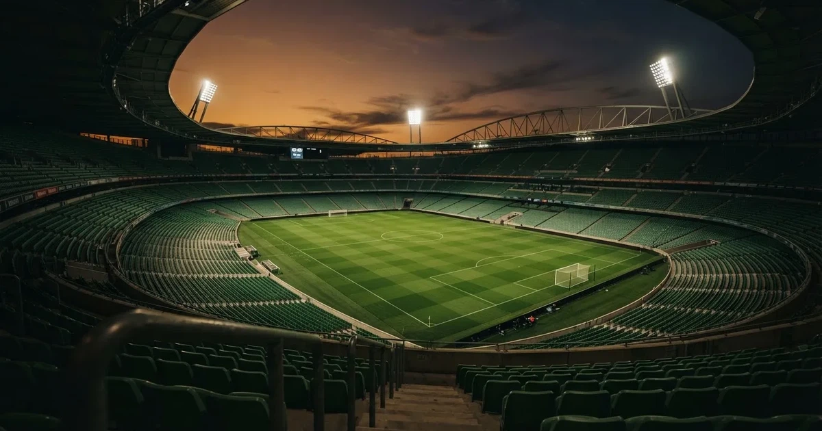Een leeg voetbalstadion met lichtmasten bij schemering