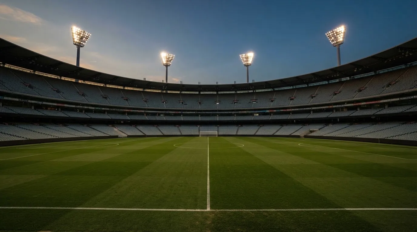 Een leeg voetbalstadion met lichtmasten bij schemering