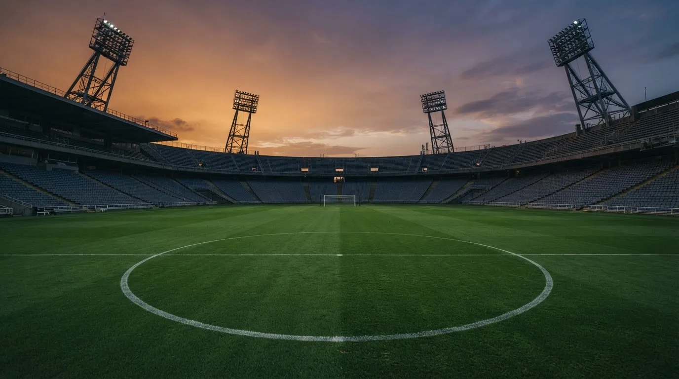 Een leeg voetbalstadion met lichtmasten bij schemering