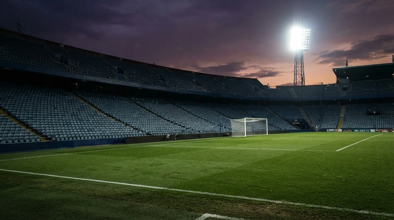 Een leeg voetbalstadion met lichtmasten bij schemering
