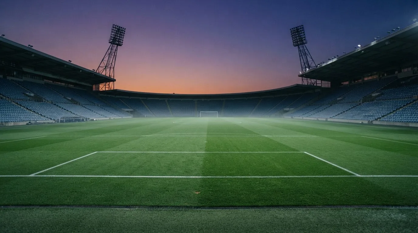Een leeg voetbalstadion met lichtmasten bij schemering