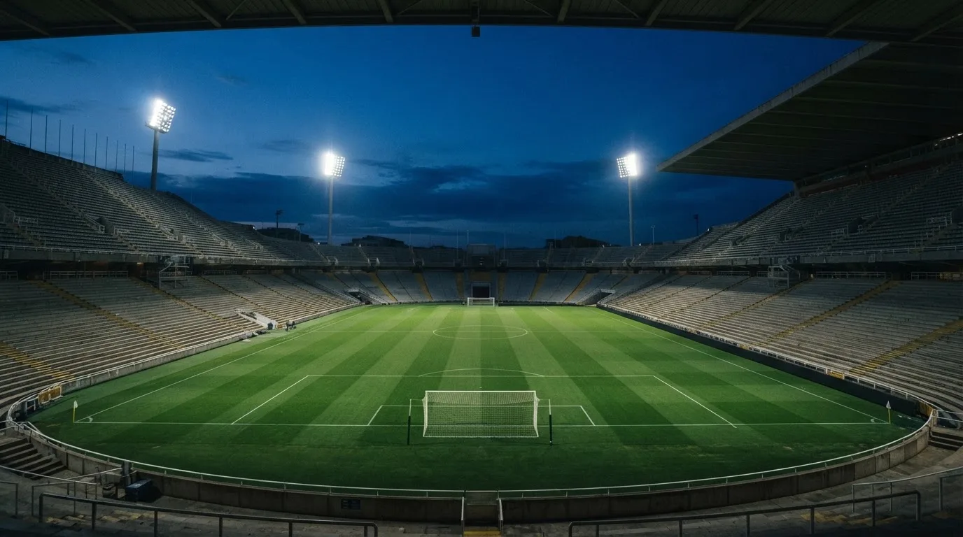 Een leeg voetbalstadion met lichtmasten bij schemering