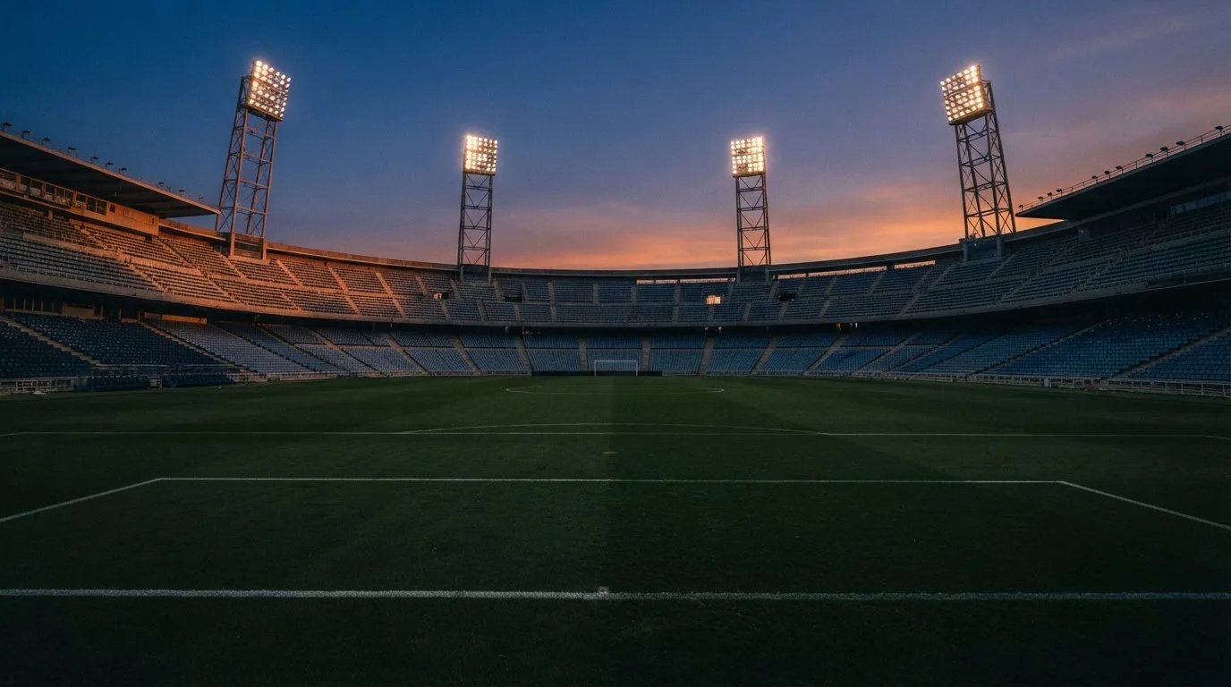 Een leeg voetbalstadion met lichtmasten bij schemering