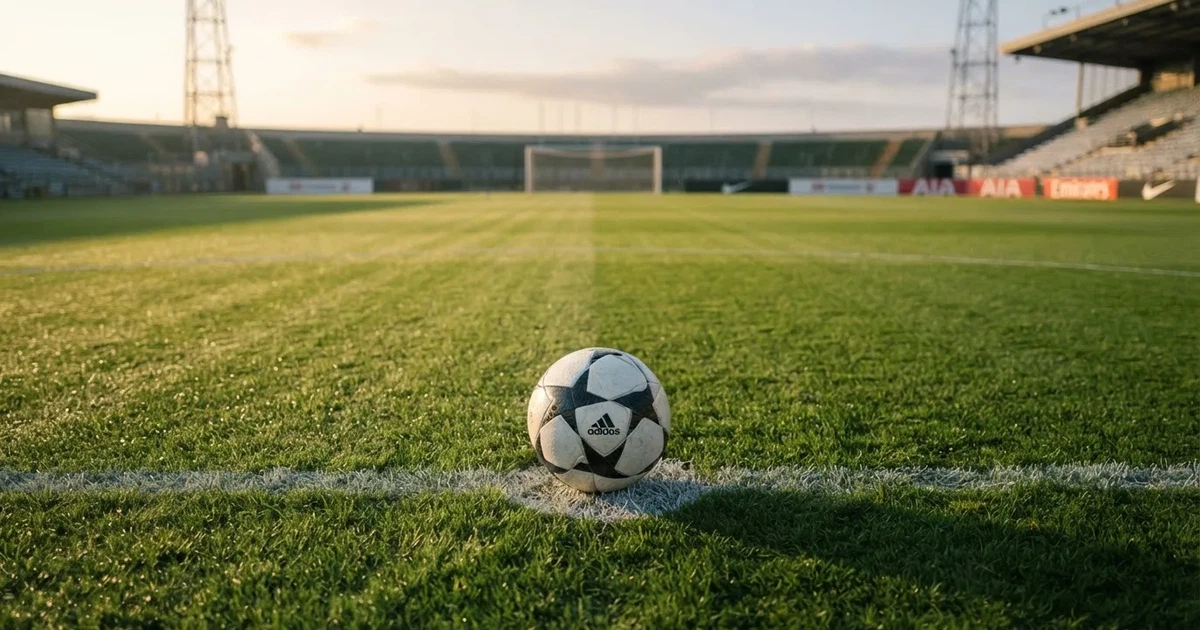 Een voetbal op de middenstip van een grasveld in het ochtendlicht