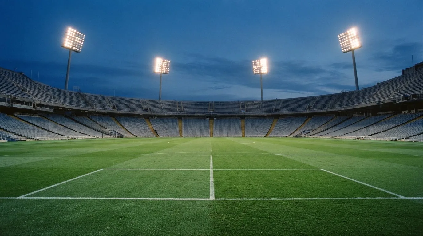 Een leeg voetbalstadion met lichtmasten bij schemering