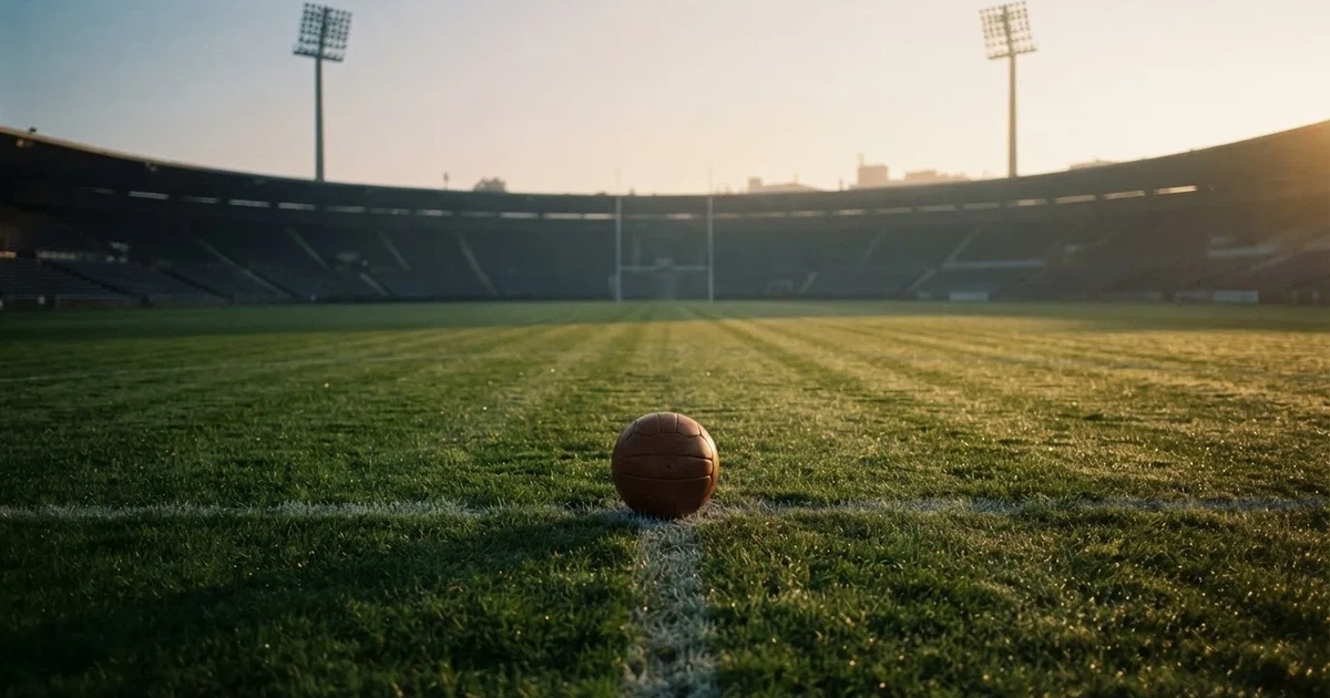 Een voetbal op de middenstip van een grasveld in het ochtendlicht