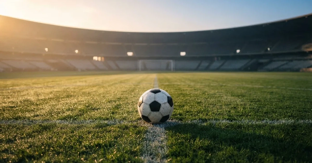 Een voetbal op de middenstip van een grasveld in het ochtendlicht