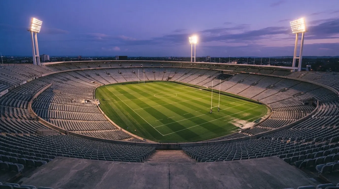 Een leeg voetbalstadion met lichtmasten bij schemering