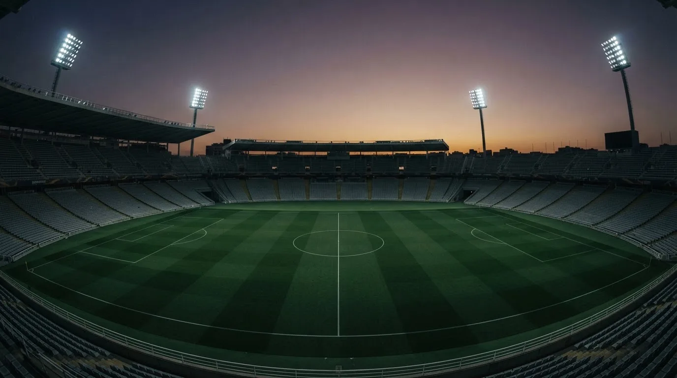 Een leeg voetbalstadion met lichtmasten bij schemering